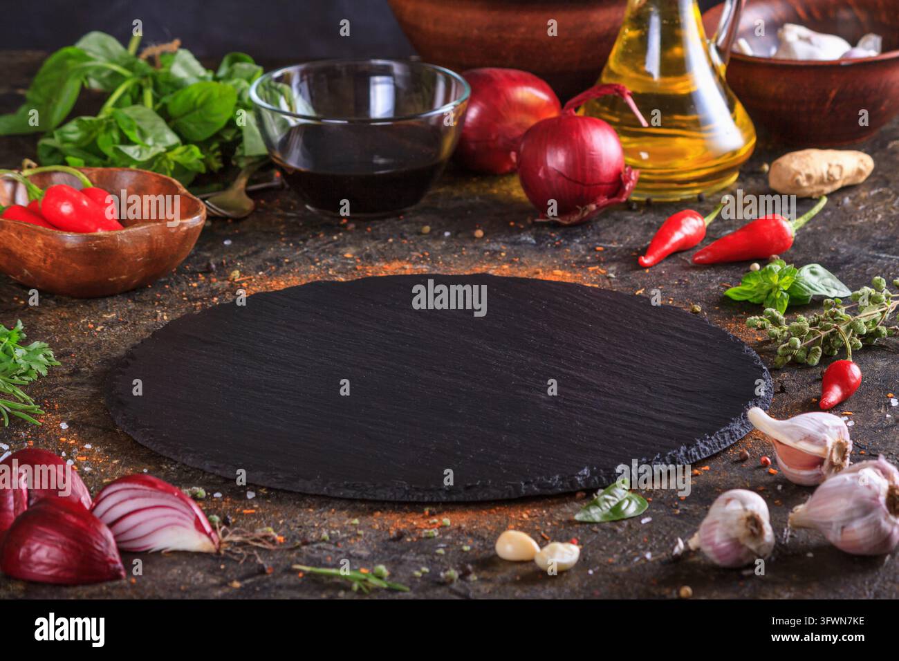 Sfondo culinario con piatto di ardesia da cucina, olio d'oliva e verdure. Messa a fuoco selettiva con spazio di copia per il testo Foto Stock