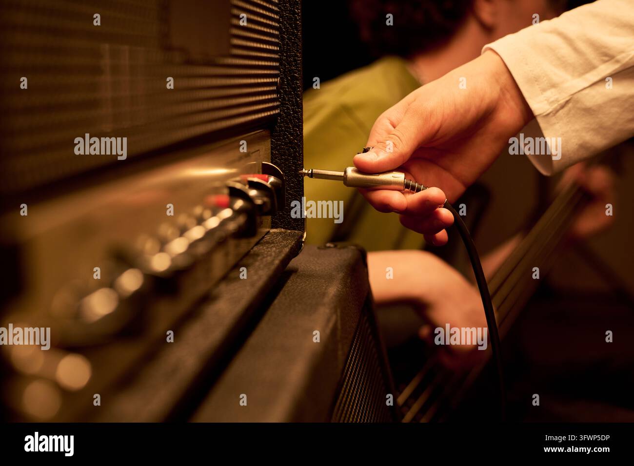 Adolescente che inserisce un cavo audio nell'amplificatore durante la prova Foto Stock