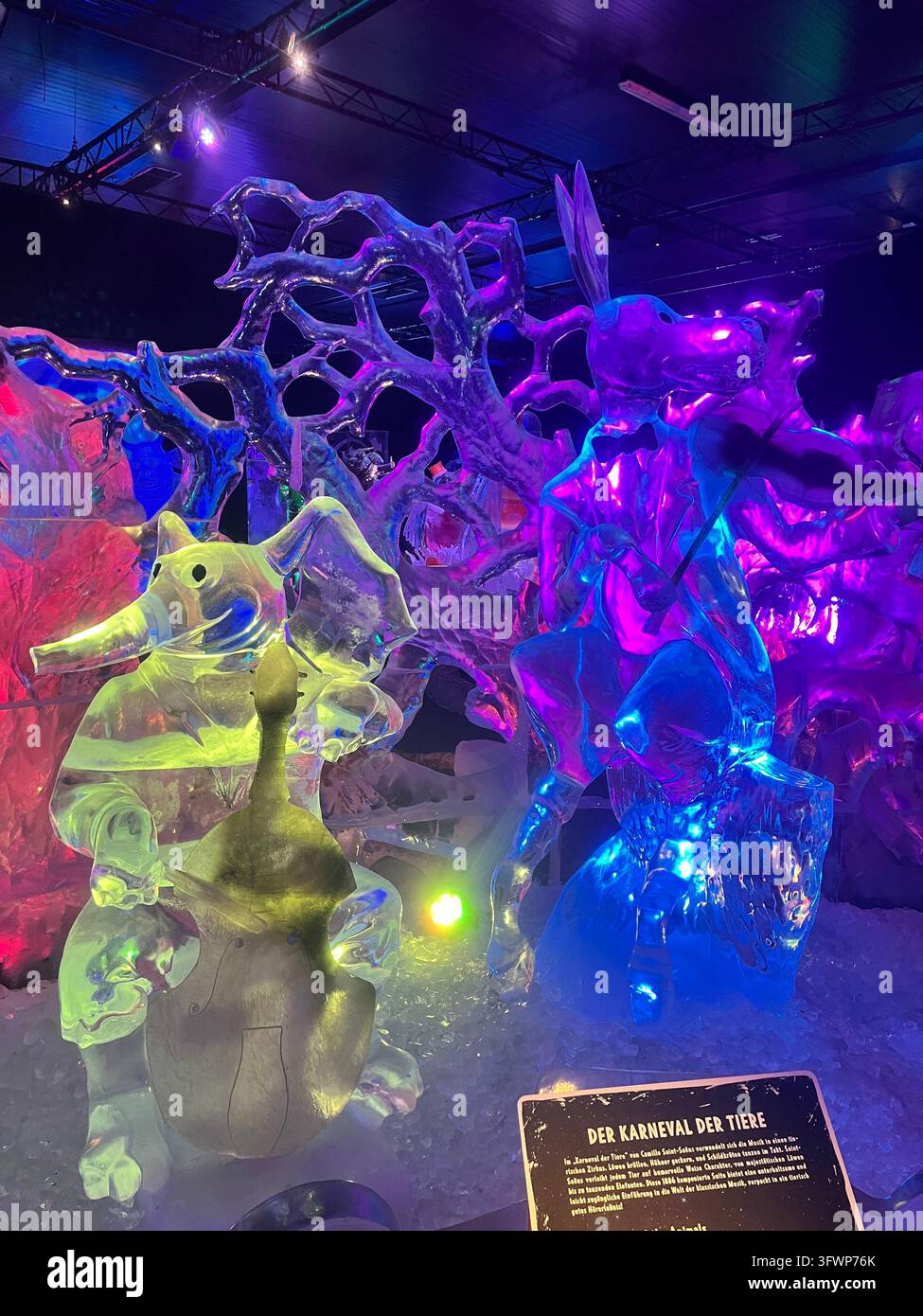 Sculture di ghiaccio di un elefante che suona il violoncello e di un canguro del Carnevale degli animali, illuminate da luci colorate in una mostra. Foto Stock