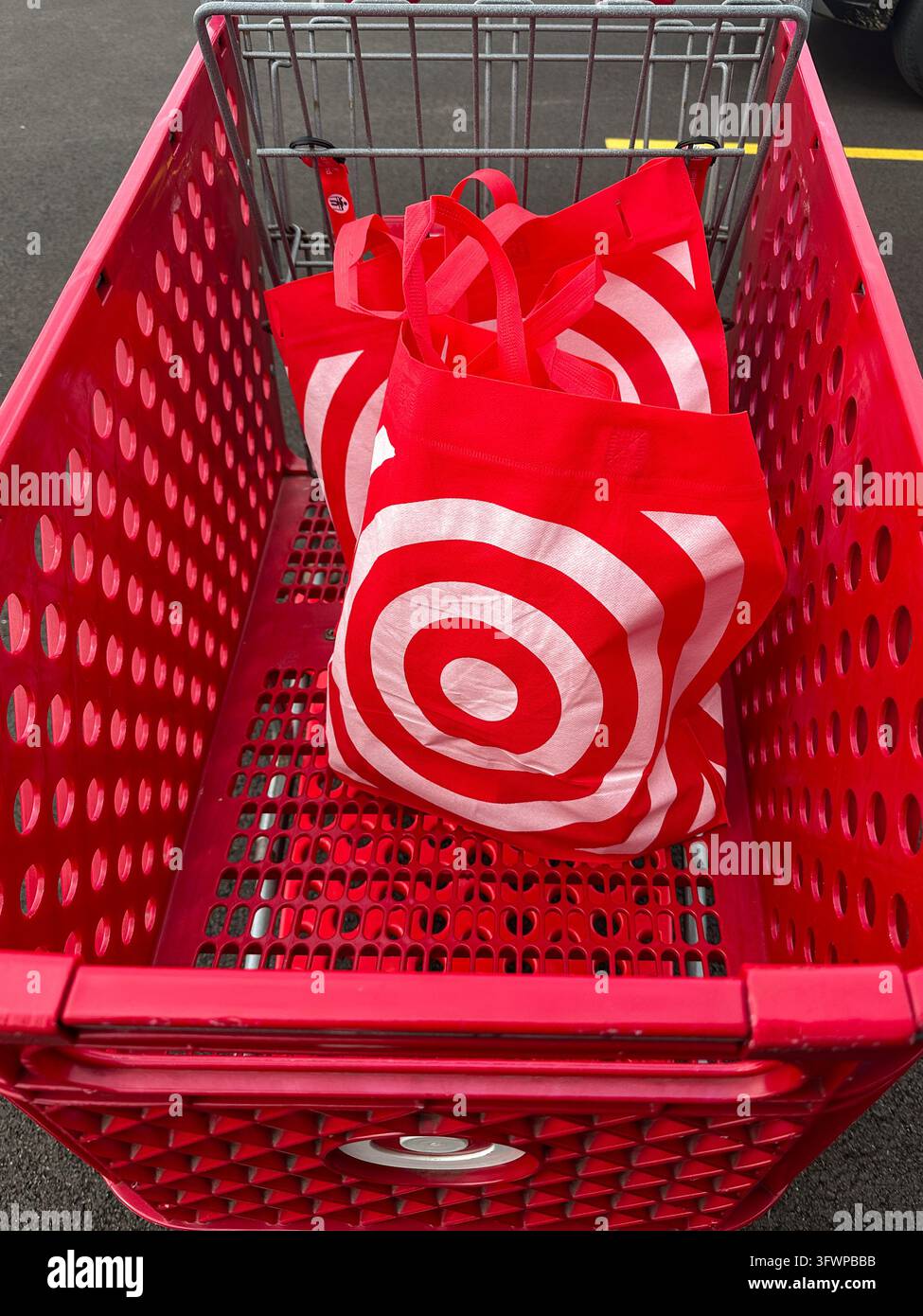 Borse della spesa riutilizzabili all'interno di un carrello della spesa in plastica rosso in un parcheggio. Valparaiso, IN USA - 22 settembre 2026 - Immagine stock catturata con smartphone