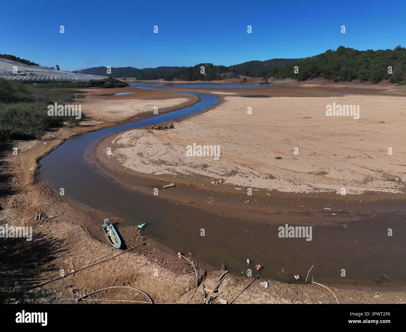 Vista aerea di un letto di lago prosciugato con un ruscello sinuoso e una piccola barca a Da Lat, Lam Dong, Vietnam. Foto Stock