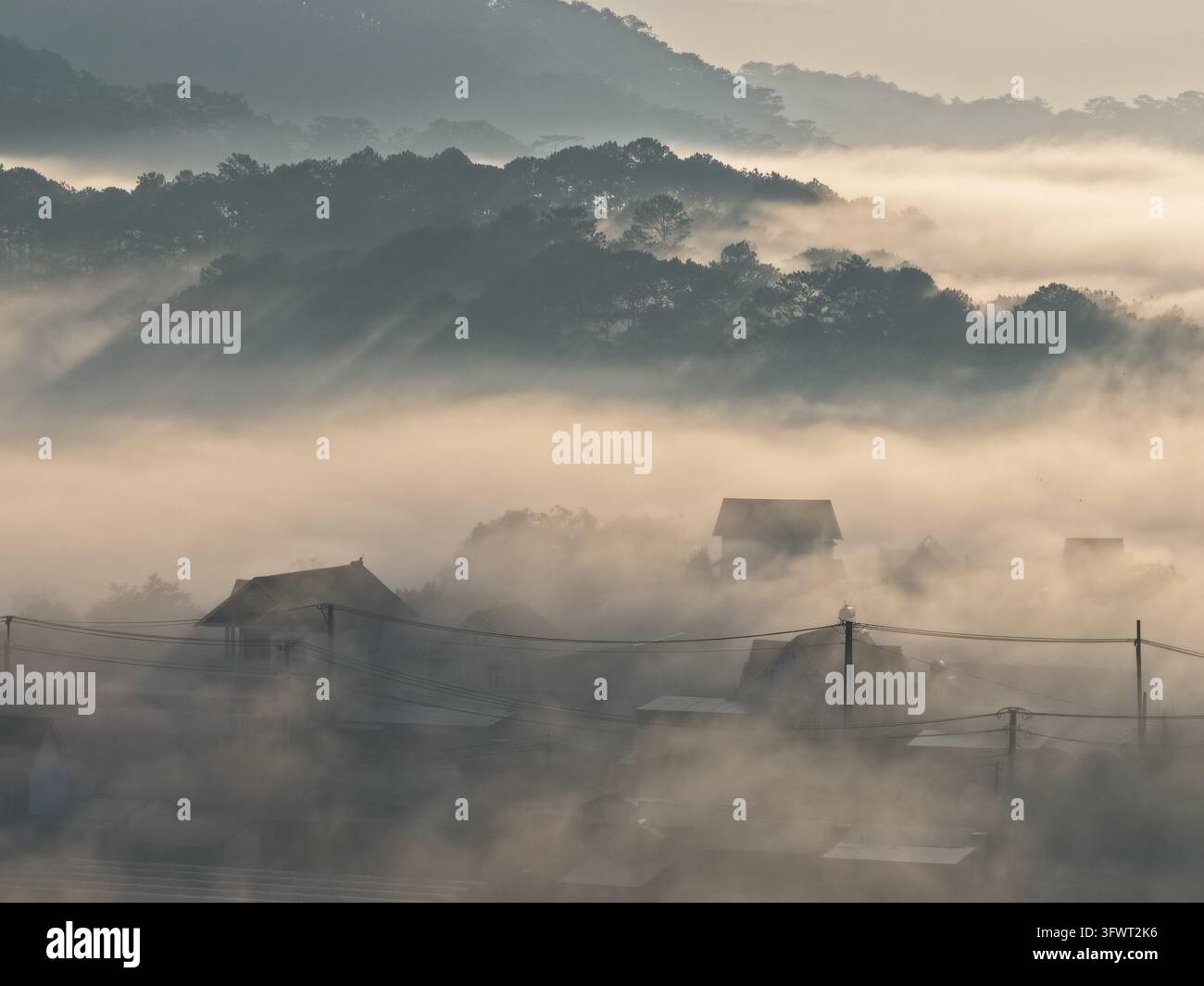 Vista aerea di una fitta nebbia mattutina che si sposta sulle colline e sui tetti delle case a Da Lat, Lam Dong, Vietnam Foto Stock