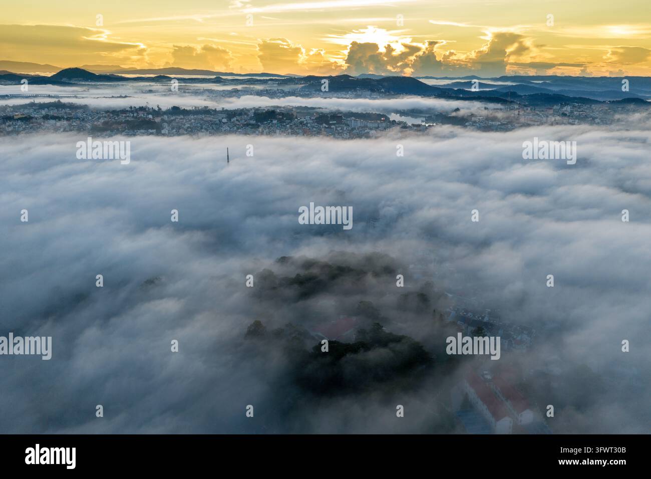 Vista aerea della città di Da Lat all'alba, con un fitto mare di nuvole che copre il paesaggio, rivelando colline lontane e tetti a Da Lat, Lam Dong Foto Stock