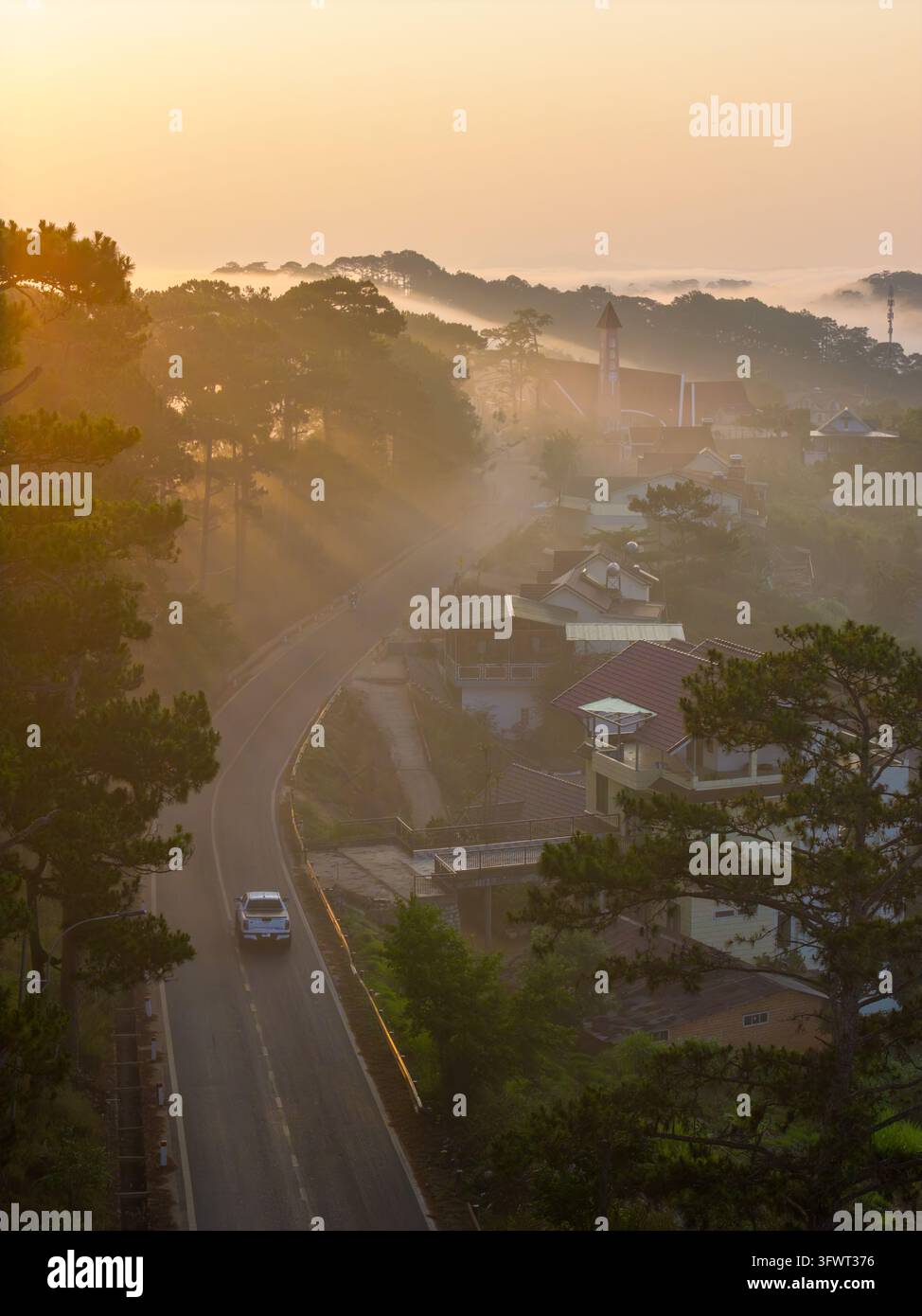 Vista aerea di una strada tortuosa attraverso un paesaggio nebbioso coperto di pini all'alba a Da Lat, Lam Dong, Vietnam. Foto Stock