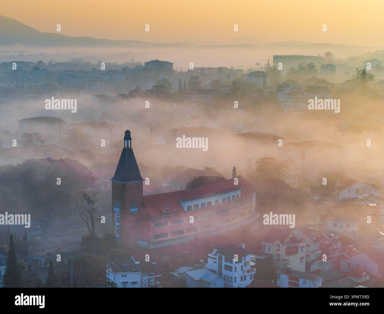 Vista aerea del collegio pedagogico storico di Da Lat con il suo caratteristico campanile che si erge sopra la nebbia mattutina che copre la città di Da Lat, Lam Foto Stock