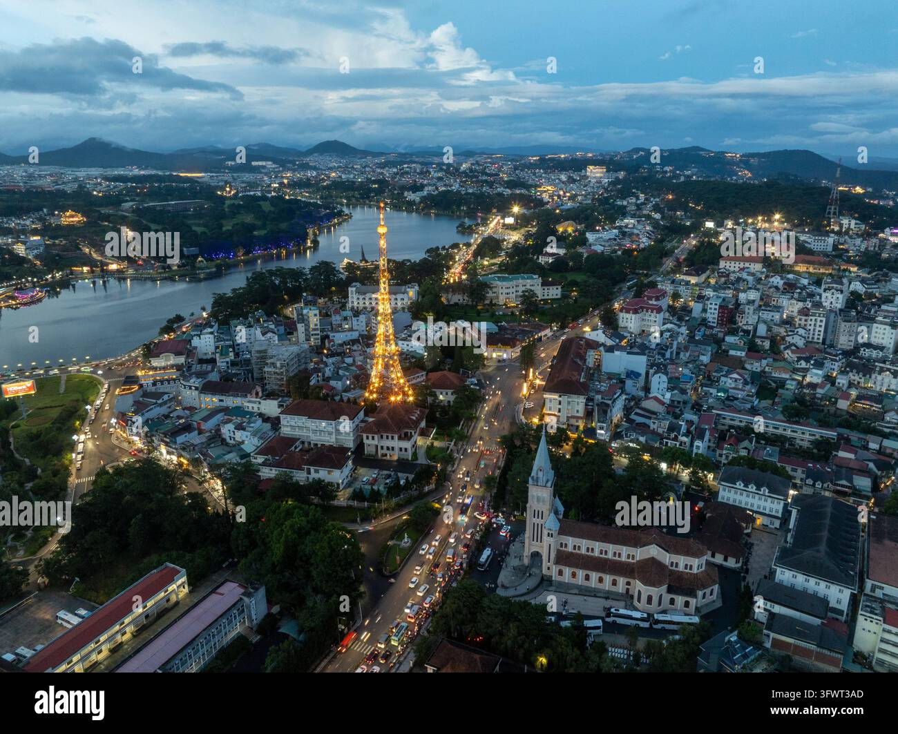 Vista aerea della torre di telecomunicazioni illuminata e della cattedrale di Da Lat vicino al lago Xuan Huong al crepuscolo a Da Lat, Lam Dong, Vietnam. Foto Stock