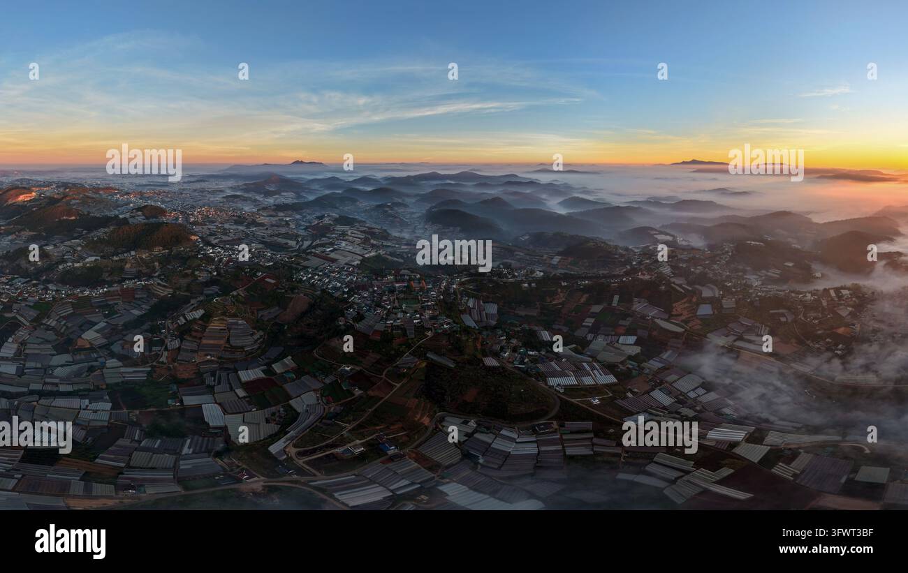 Vista aerea delle montagne nebbiose e delle serre agricole all'alba a Da Lat, Lam Dong, Vietnam. Foto Stock