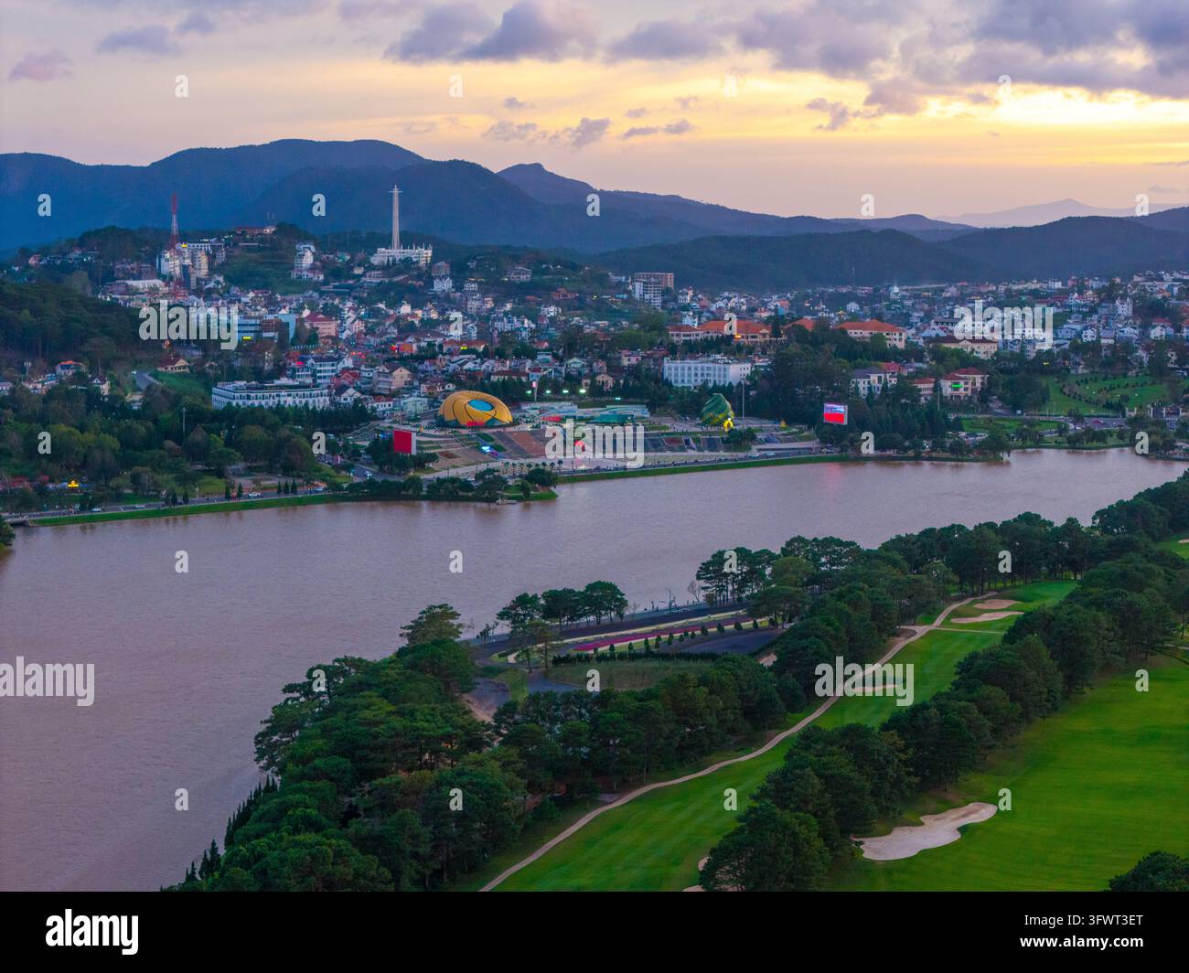 Veduta aerea del lago Xuan Huong circondato da rigogliose foreste di pini, un campo da golf e il paesaggio urbano di Da Lat, Lam Dong, Vietnam. Foto Stock
