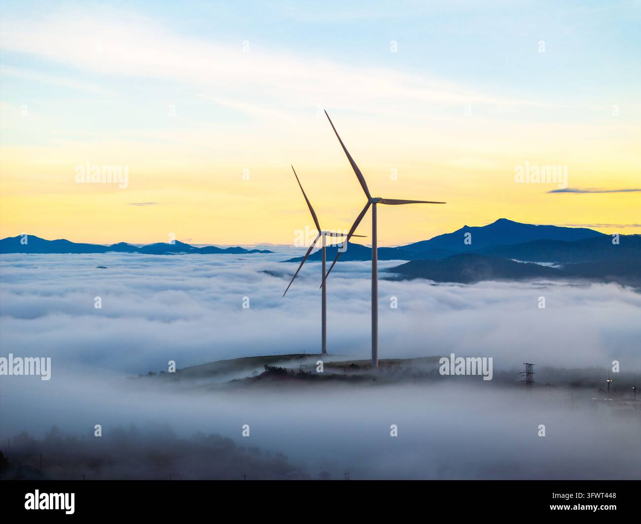 Vista aerea di turbine eoliche che si ergono sopra un mare di nuvole al tramonto nelle terre alte di Da Lat, Lam Dong, Vietnam. Foto Stock