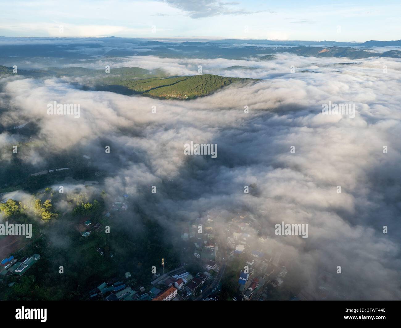 Vista aerea della città di Da Lat parzialmente oscurata da uno spesso strato di nuvole mattutine su colline ondulate e foreste di pini a Da Lat, Lam Dong, Vietnam. Foto Stock