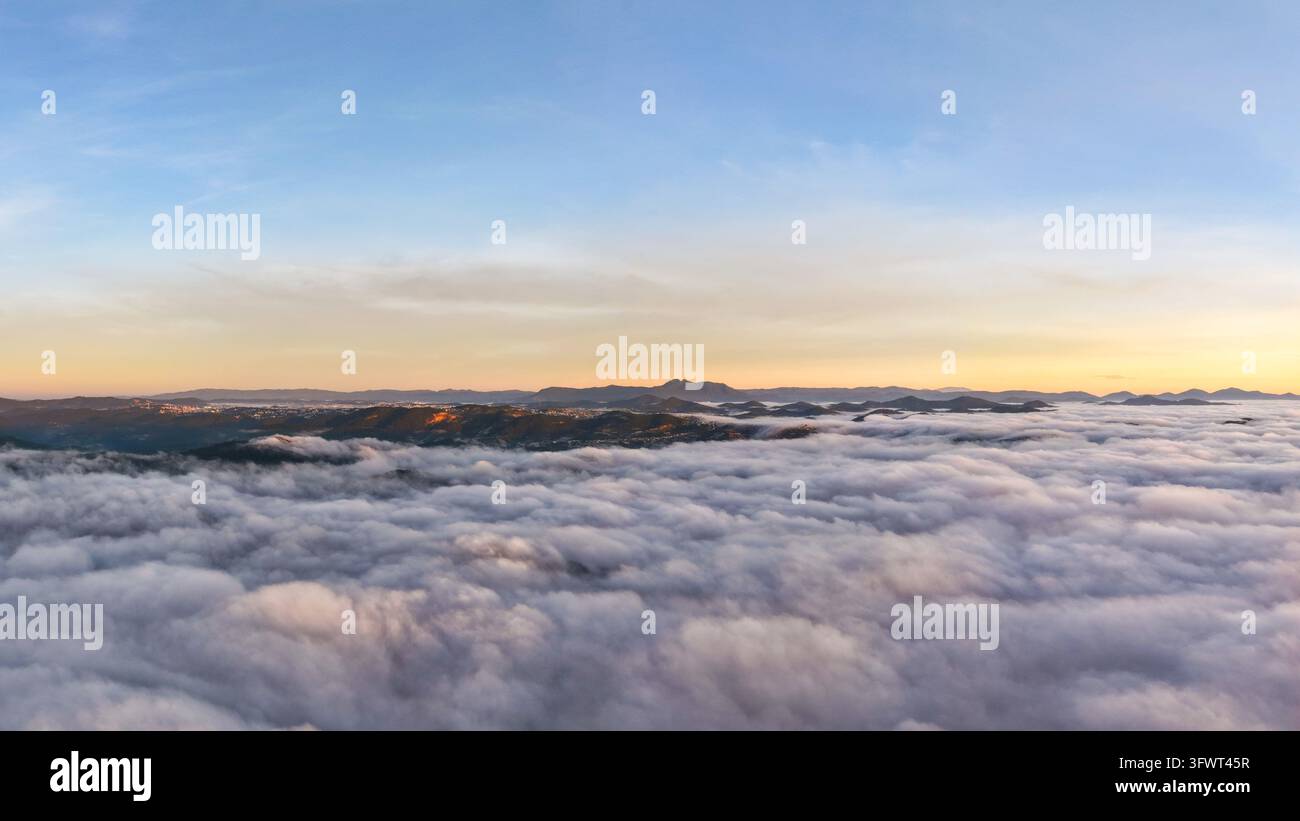 Vista aerea di un vasto mare di nuvole che copre il paesaggio montano all'alba a Da Lat, Lam Dong, Vietnam. Foto Stock