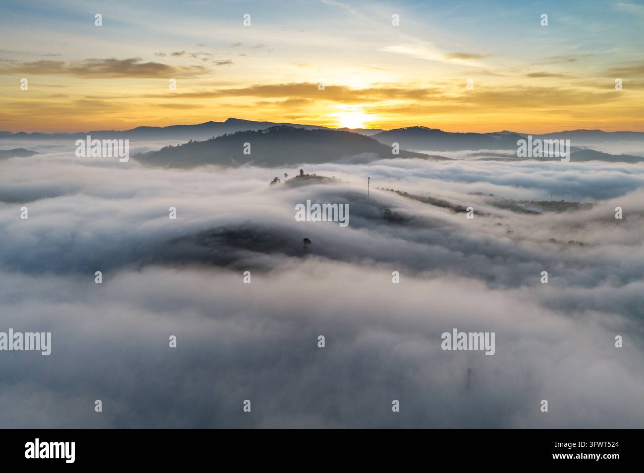 Vista aerea dell'alba su un mare di nuvole che copre il paesaggio montuoso di Da Lat, Lam Dong, Vietnam. Foto Stock