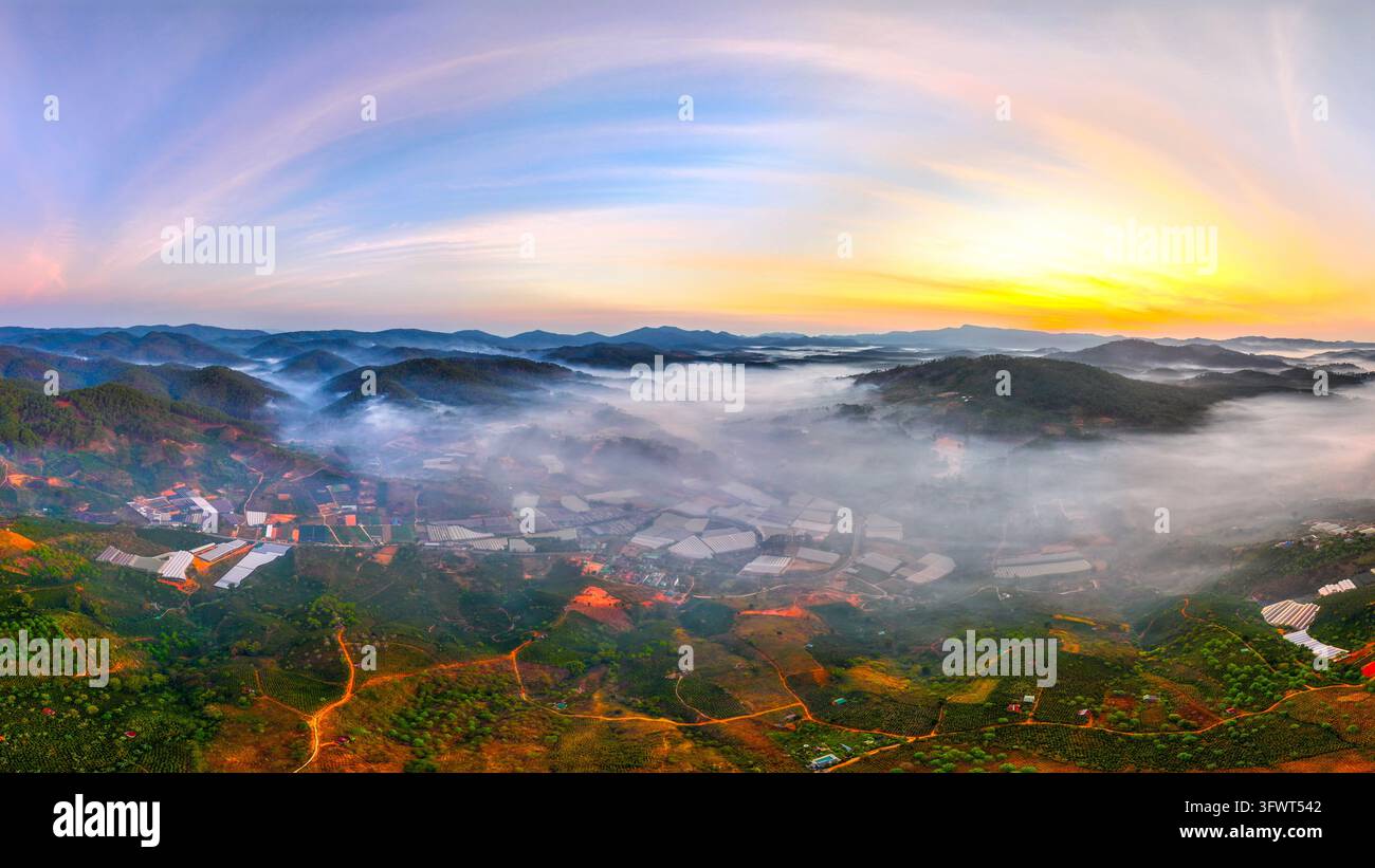 Vista aerea del paesaggio nebbioso di Da Lat all'alba, con colline ondulate, serre agricole e un cielo vivace su Da Lat, Lam Dong, V Foto Stock