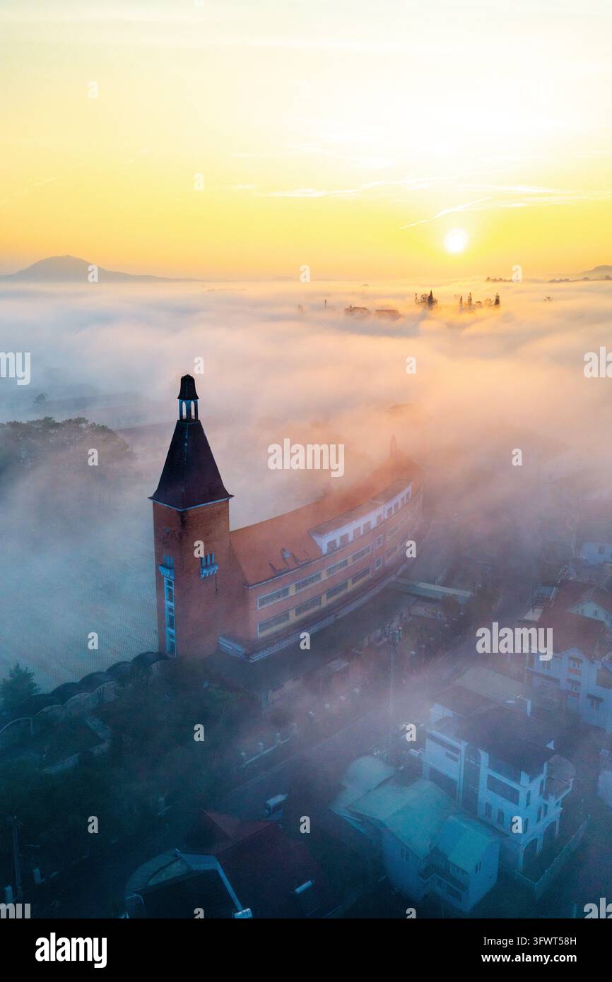 Vista aerea del Collegio Pedagogico di Da Lat circondato da una fitta nebbia mattutina all'alba a Da Lat, Lam Dong, Vietnam. Foto Stock