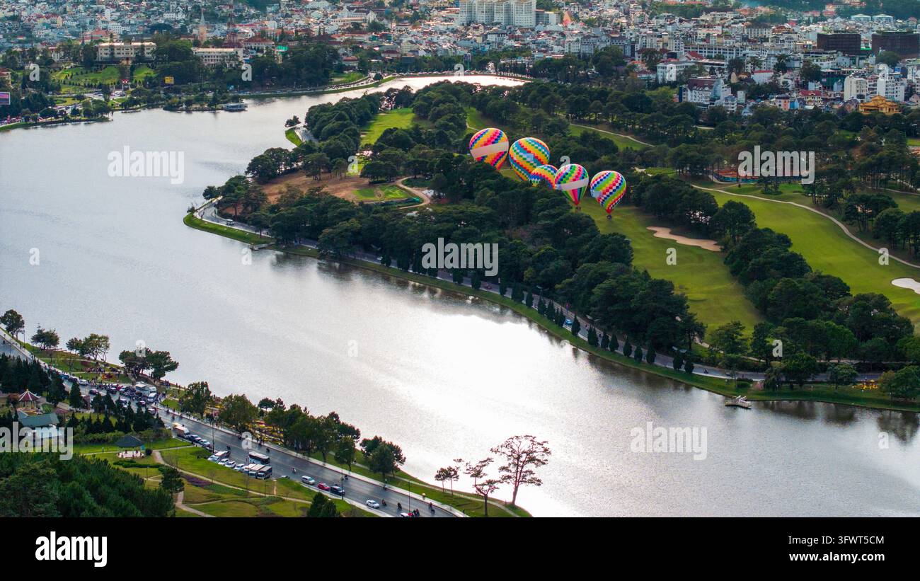Vista aerea di colorati palloni aerostatici che galleggiano sopra il rigoglioso parco verde e il lago Xuan Huong a Da Lat, Lam Dong, Vietnam. Foto Stock