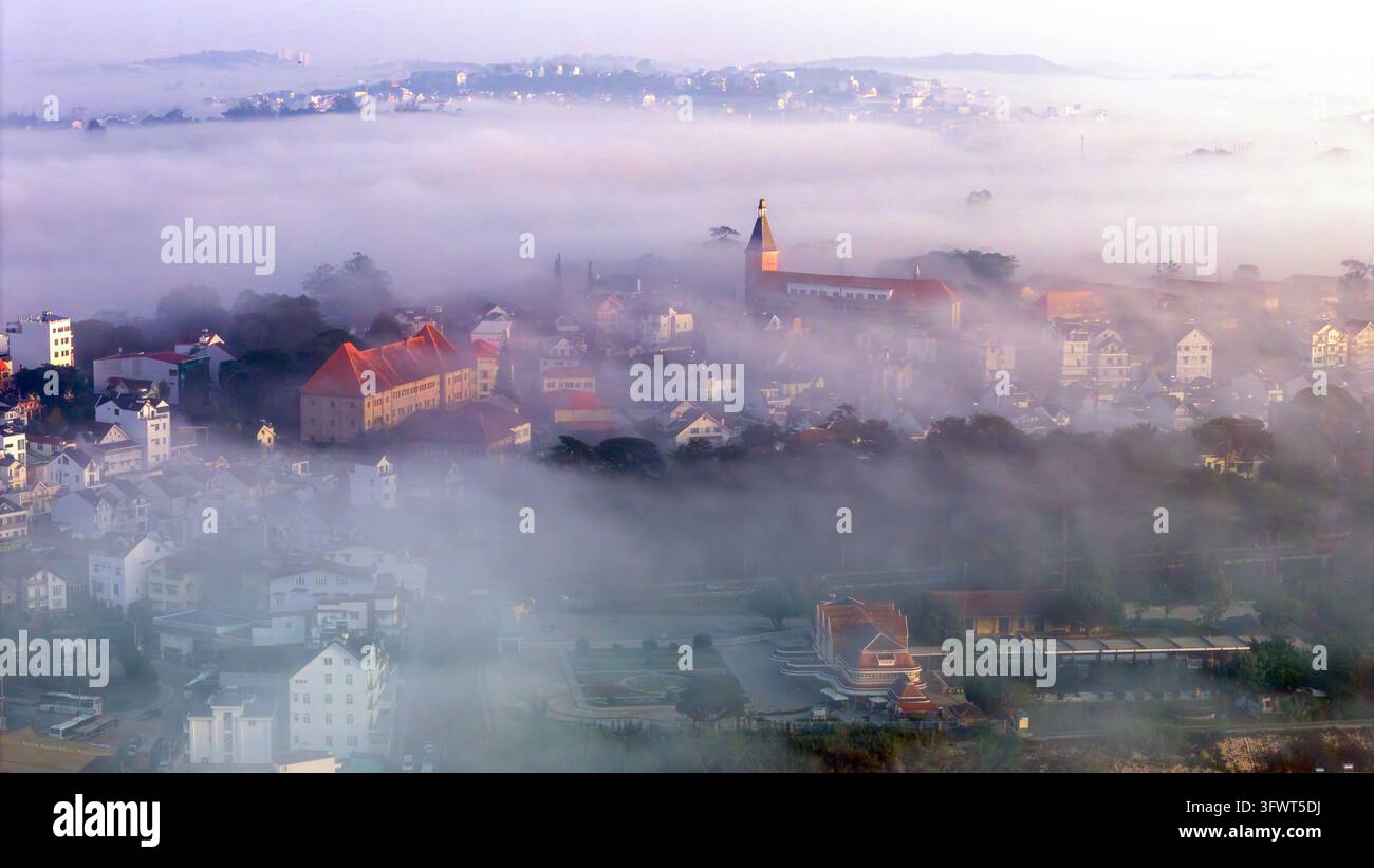 Vista aerea della cattedrale di Da Lat circondata dalla nebbia mattutina e dai tetti in stile coloniale nella città di Da Lat, Lam Dong, Vietnam. Foto Stock
