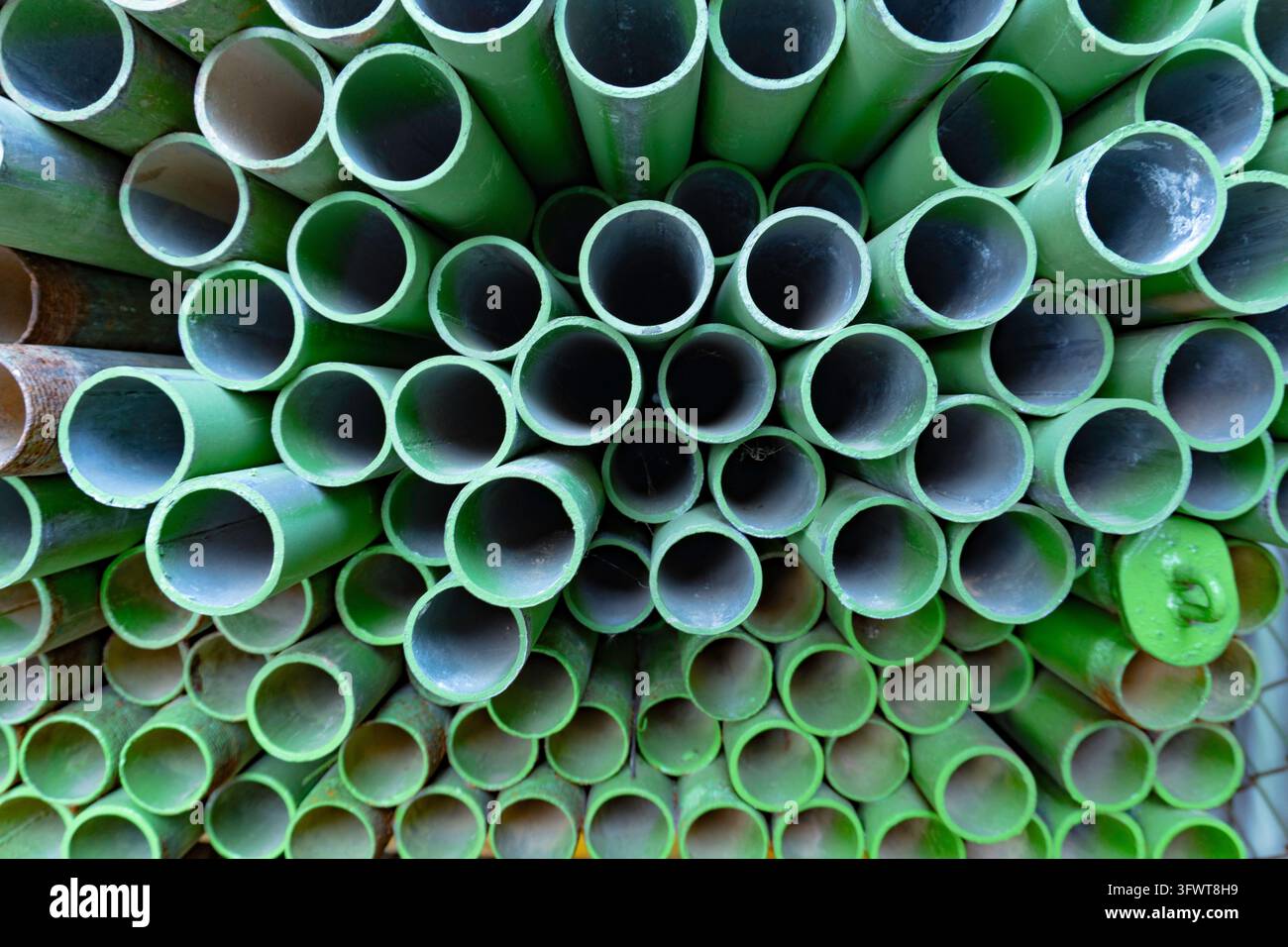 Pila di tubi di ponteggio in acciaio verniciati di verde Foto Stock