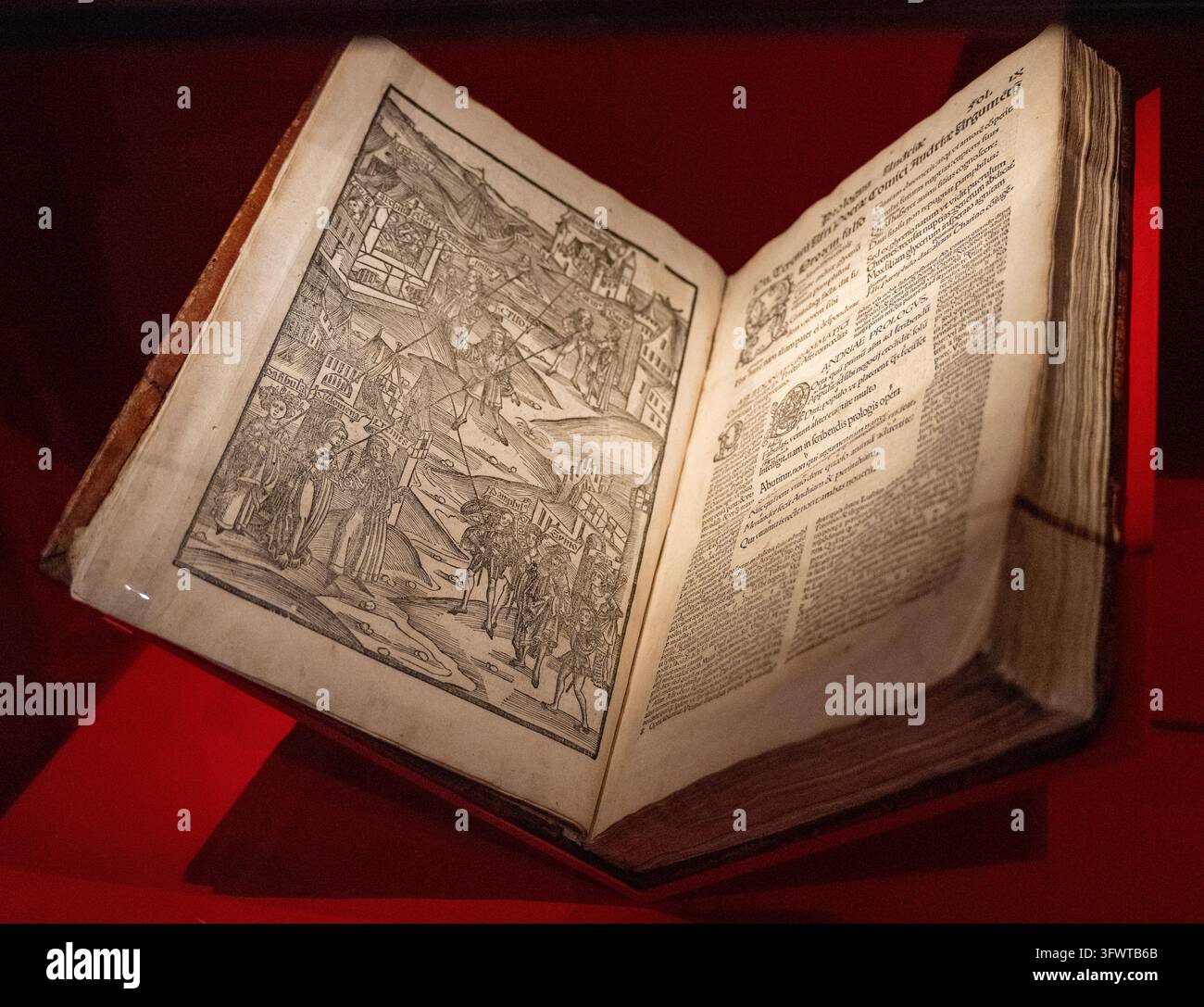 Un libro storico aperto con un'illustrazione teatrale e testo latino, esposto su un supporto rosso al Museo Storico di Strasburgo in Alsazia, Francia Foto Stock
