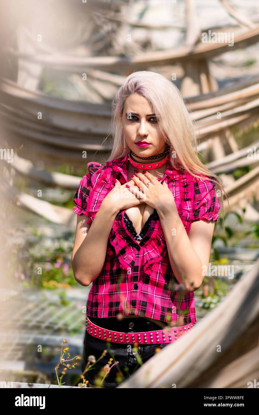 Bella donna ritratto con punk make up e vestito con i capelli decolorati in posa di un abbandonato casa verde dove la natura ha preso il suo pedaggio Foto Stock