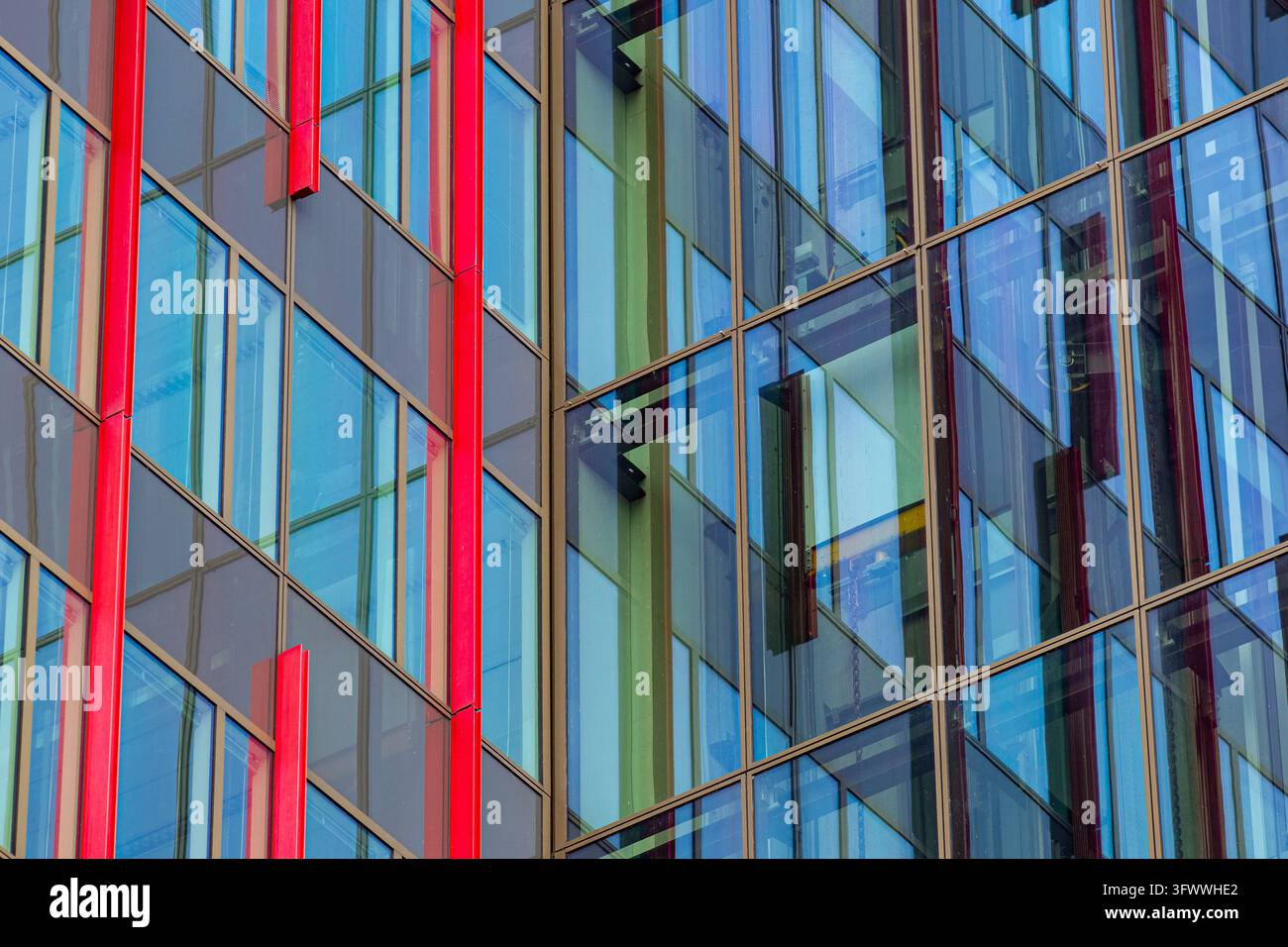 Vista della moderna facciata in vetro del World Trade Center Almere, con finestre riflettenti ed elementi architettonici verticali rossi vivaci ad Almere Foto Stock