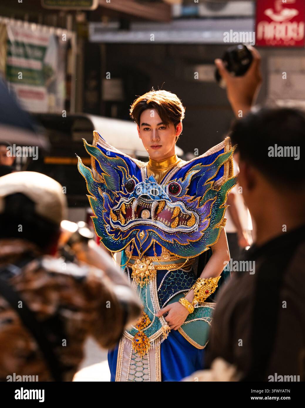 Bangkok, Thailandia - 1 febbraio 2026: Un giovane uomo che indossa un elaborato costume a tema drago blu e oro si trova all'aperto mentre... Foto Stock