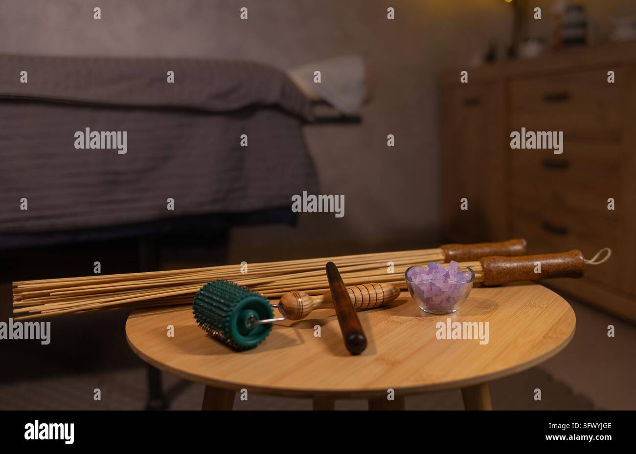 Strumenti per la massoterapia su tavolo di legno in una confortevole sala di trattamento benessere Foto Stock