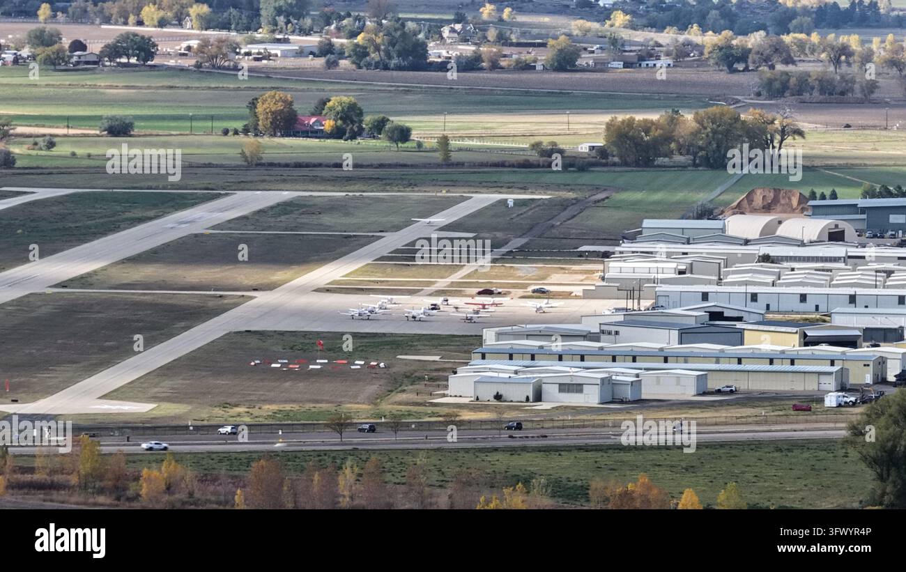 Vista aerea dell'aeroporto Vance Brand con piste, file di hangar, piccoli aerei parcheggiati sulla pista e il paesaggio rurale circostante a Longmon Foto Stock