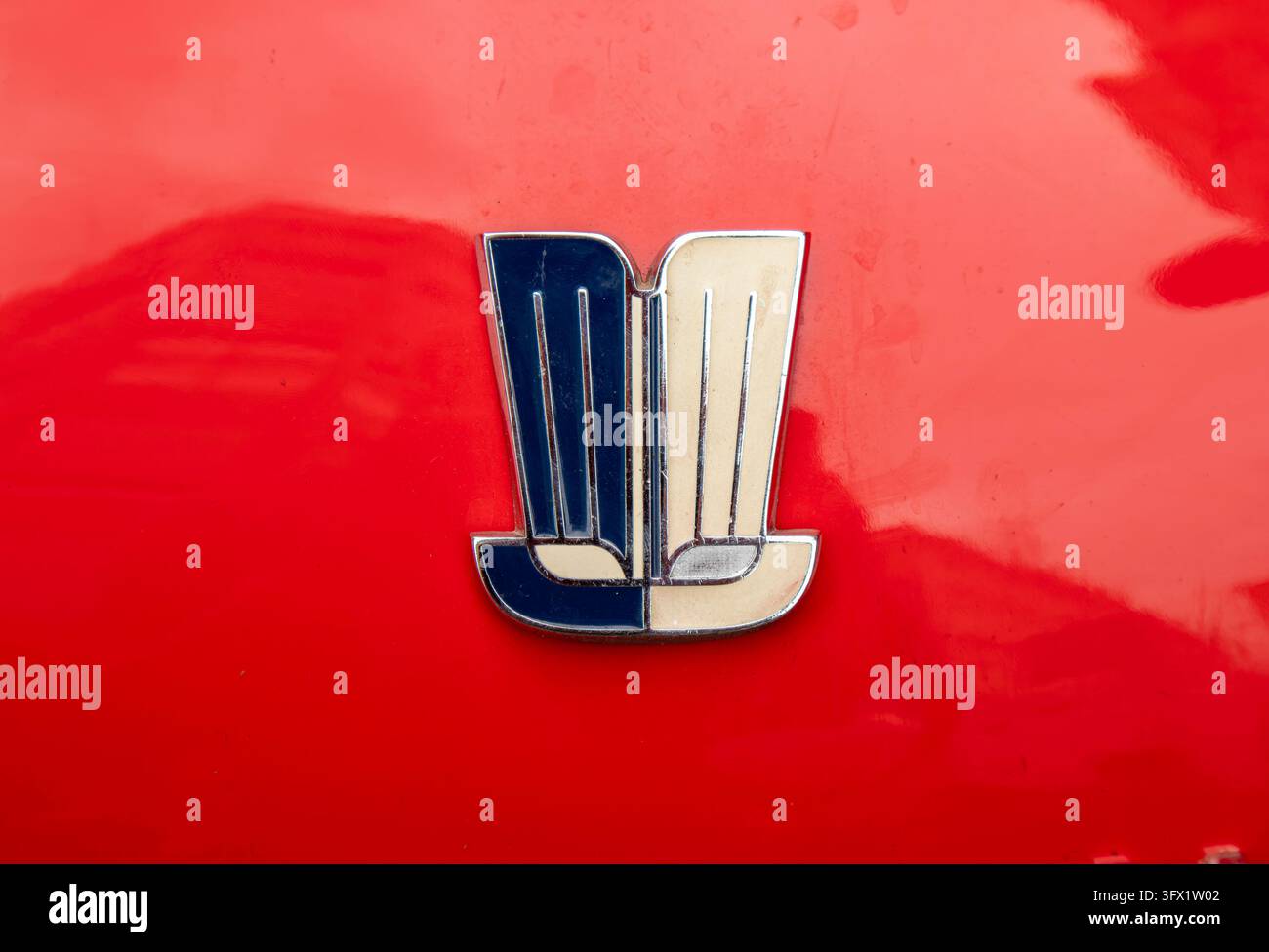 GANDIA, SPAGNA - 4 OTTOBRE 2026: Emblema smaltato di automobile vintage con design blu e bianco montato sulla carrozzeria rossa lucida di una classica ca Foto Stock