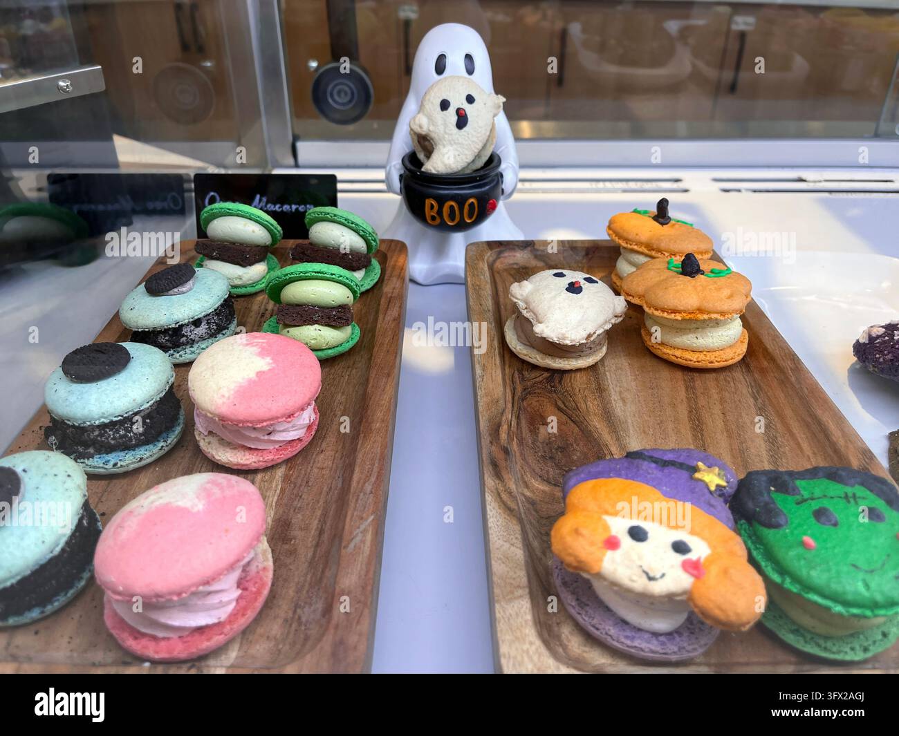 Vetrina da panetteria con tavole di legno e macarons colorati di Halloween a forma di fantasmi, zucche e streghe Foto Stock