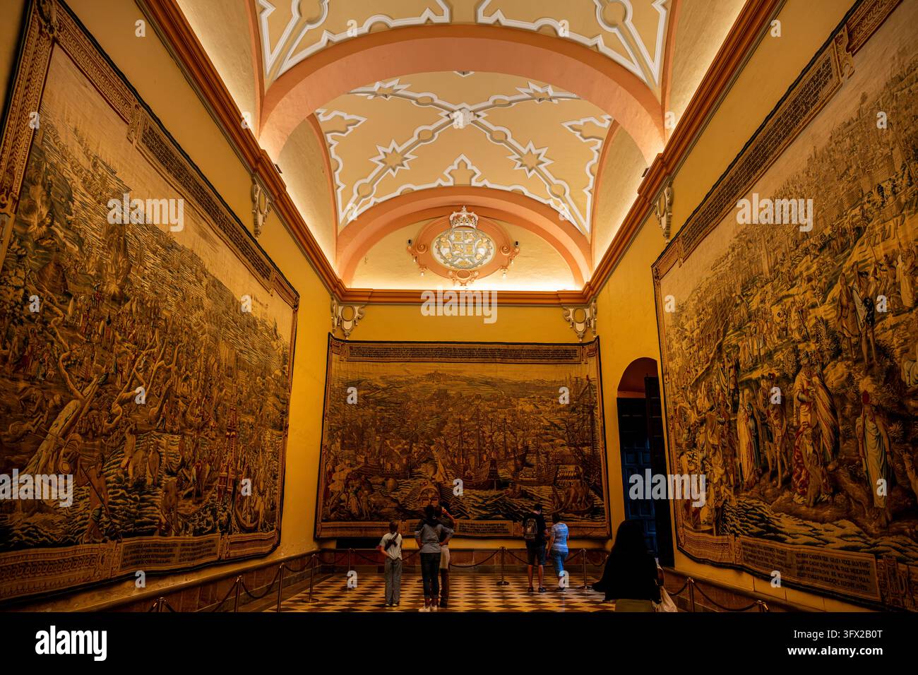 Visitatori che osservano gli arazzi della Conquista di Tunisi nella Sala degli Arazzi dell'Alcazar Reale di Siviglia, Andalusia, Spagna. Foto Stock