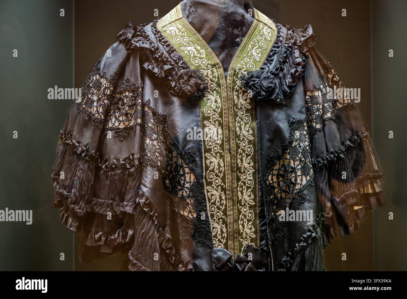 Un abito di seta nera con inserti di pizzo, balze e un bordo ricamato verde e oro è esposto su un manichino dietro il vetro in una mostra a Peso da Régua, nel distretto di Vila Real, Portogallo. Donna Antónia Ferreira indossava questo vestito. La sede è ritenuta essere il Museu do Douro. Il bordo presenta rampicanti e foglie. Foto Stock