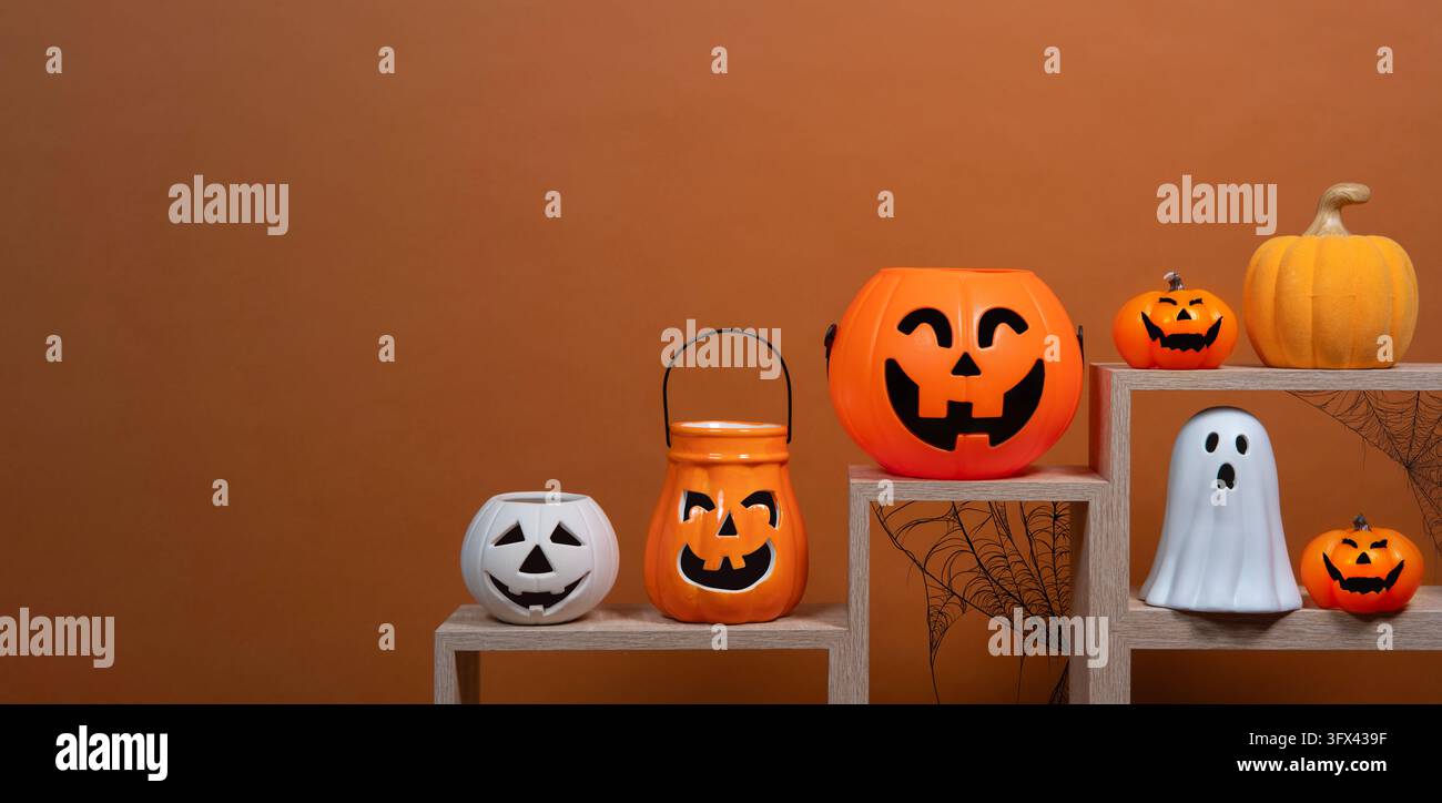 Vista frontale di un vaso di ceramica bianco a forma di zucca, quattro vasi arancioni a forma di zucca con volti neri, un fantasma bianco e una zucca di ceramica, tutti disposti Foto Stock
