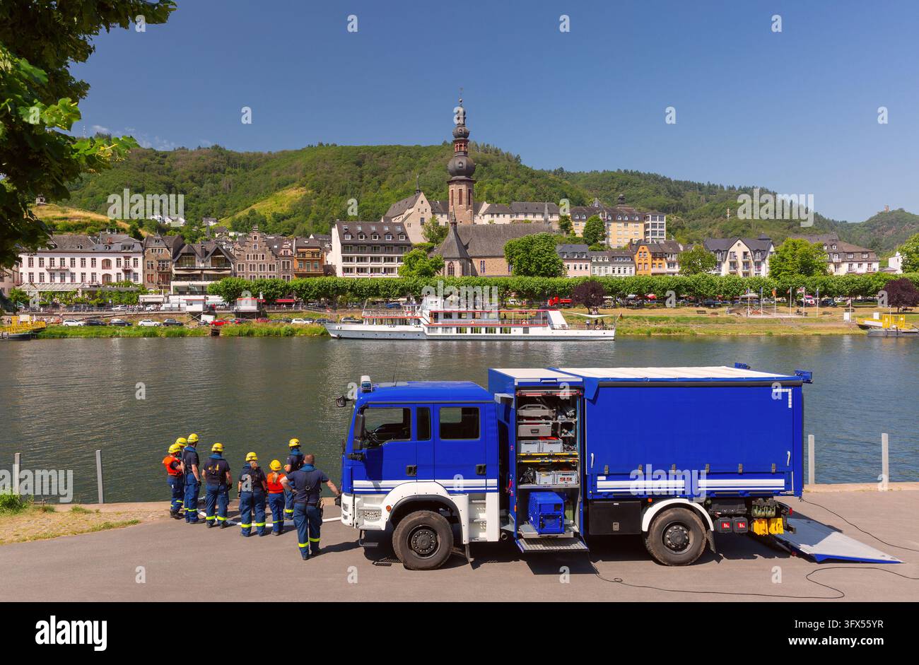 Vigili del fuoco riuniti accanto a un camion di emergenza blu sulla riva della Mosella a Cochem, Germania. Foto Stock