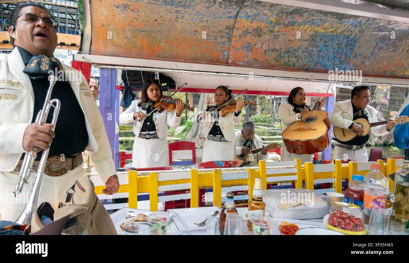 Xochimilco è noto per la sua rete di canali e per le trajineras dipinte di colori vivaci, dove i visitatori possono assumere musicisti per suonare a bordo delle barche. Foto Stock