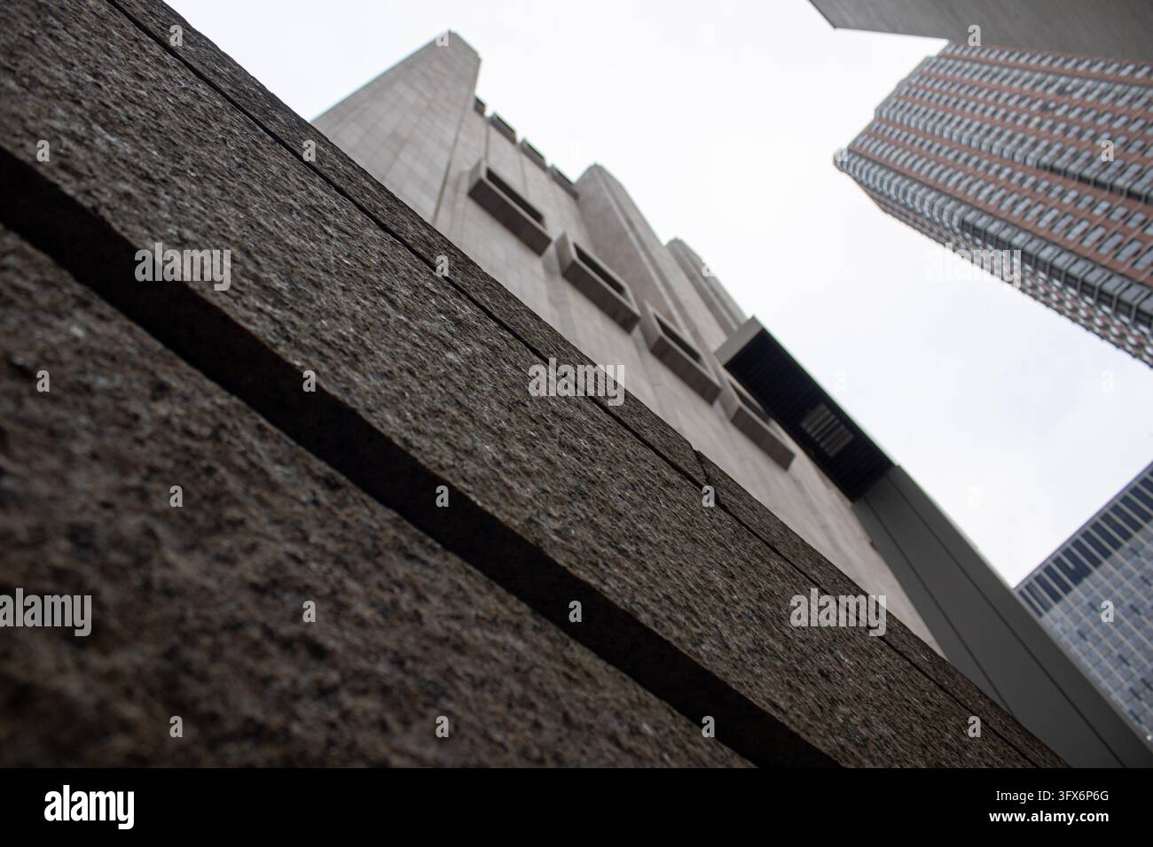 Vista diagonale a bassa angolazione del bordo in granito strutturato del 33 Thomas Street con grattacieli in vetro vicini sullo sfondo, Lower Manhattan. Foto Stock