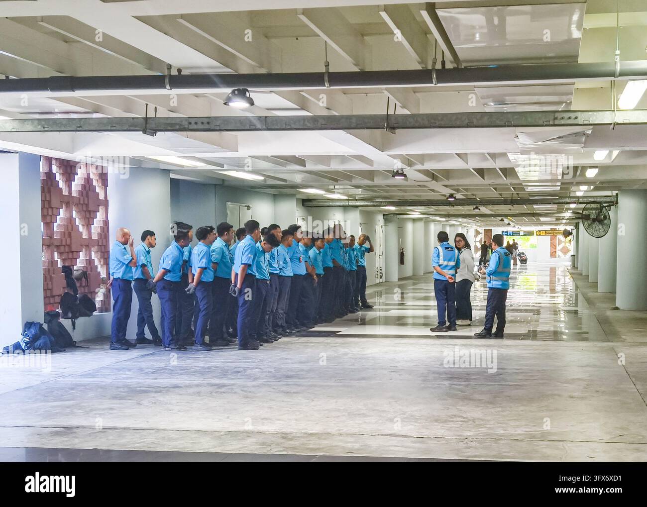 Guardie di sicurezza in uniforme allineati per un'ispezione, un briefing o un cambio turno. Aeroporto di Denpasar Bali, Indonesia Foto Stock