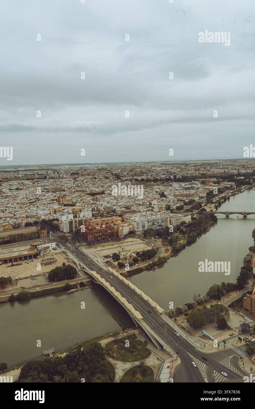 Vista aerea panoramica di Siviglia, Spagna, che mostra il fiume Guadalquivir e lo skyline della città sotto un cielo nuvoloso. Foto Stock