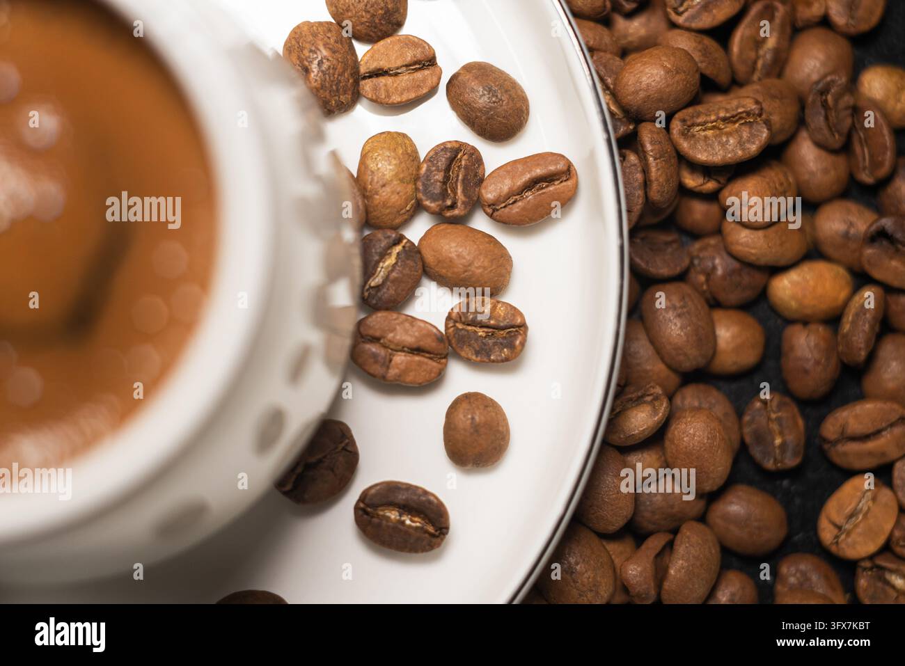 Vista superiore di chicchi di caffè e tazza su piattino bianco con sfondo marrone caldo Foto Stock
