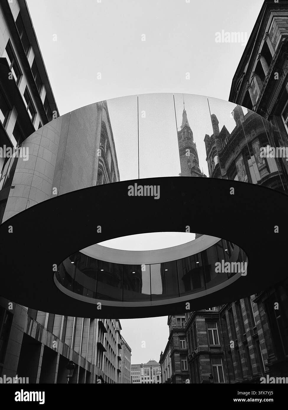 Scatto in bianco e nero della moderna passerella ad anello Tondo che riflette la torre architettonica classica del municipio di Bruxelles. Foto Stock