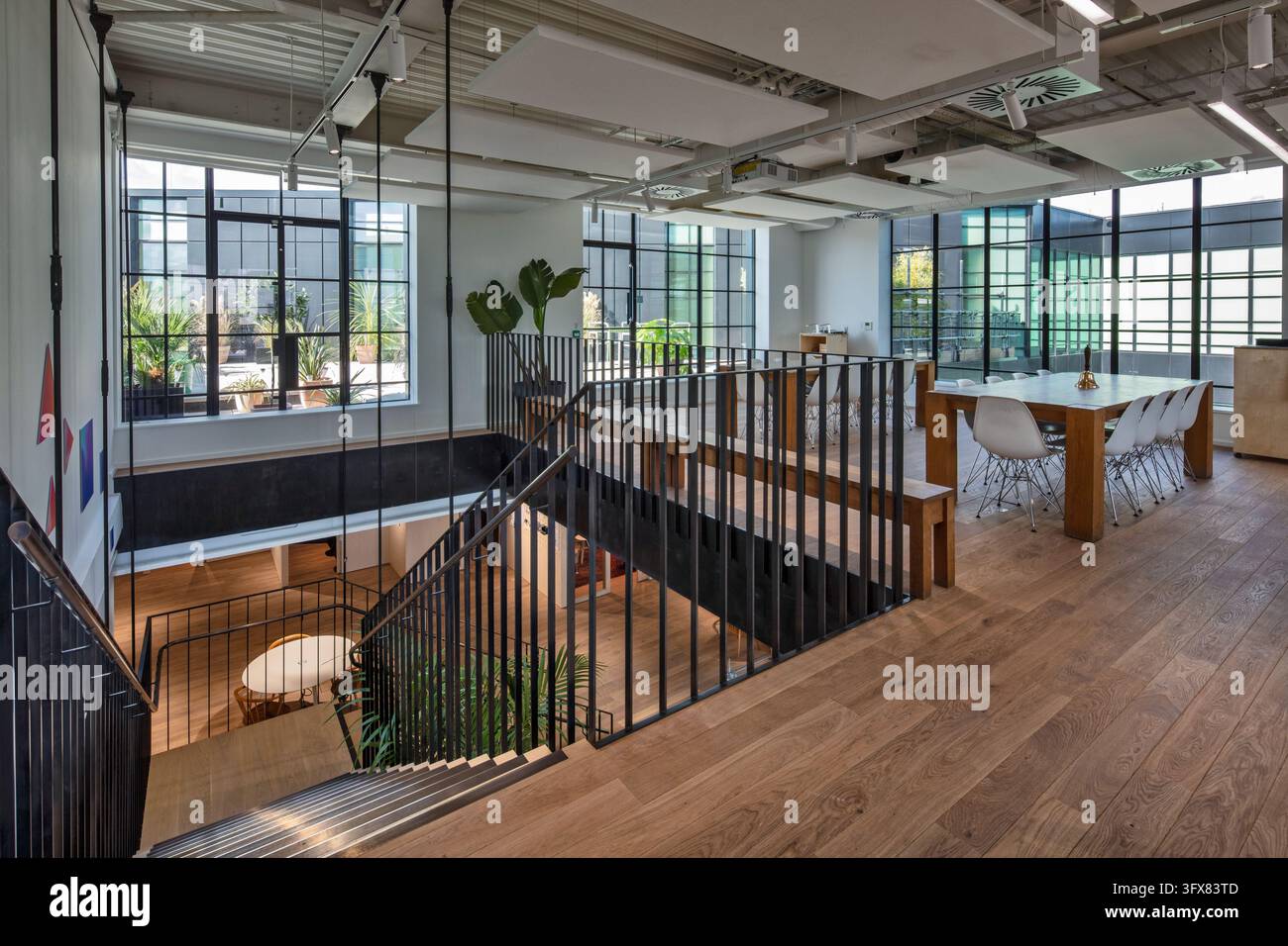 Interno dello studio di design IDEO di Londra a Clerkenwell, con uno spazio di lavoro aperto, pavimenti in legno, servizi esposti e una scala in acciaio. Foto Stock