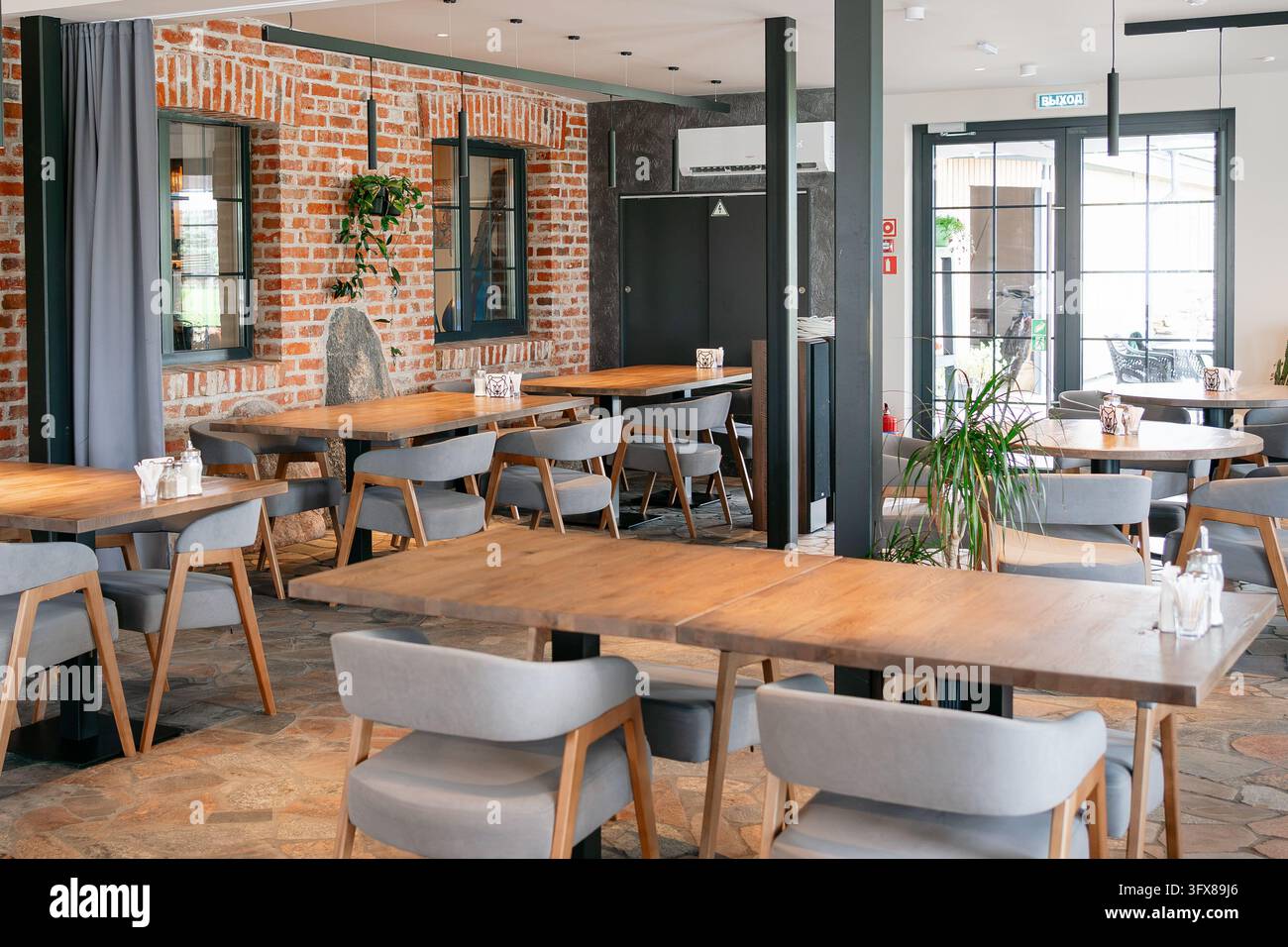 Sala da pranzo bistrot contemporanea con arredamento in stile loft industriale, mattoni a vista, sedute comode e layout spazioso per gli ospiti Foto Stock
