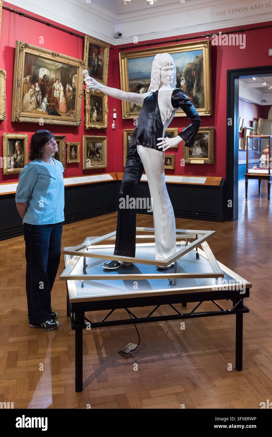 LONDRA, REGNO UNITO - 22 OTTOBRE 2026: Un membro dello staff osserva un ensemble monocromatico indossato da Freddie Mercury durante un precoce spettacolo dei Queen all'Imperial College (1973) durante un photocall per il Freddie Mercury Splendid Things Trail al V&A South Kensington a Londra, Regno Unito, il 22 ottobre 2026. Il trail, che aprirà il 24 ottobre e segna l'80º anniversario della nascita di Freddie, è stato sviluppato con Mary Austin, ex fidanzata, amica intima e confidente di Freddie per 20 anni, e celebra la carriera di Mercury attraverso costumi e accessori indossati in alcuni dei video musicali più memorabili Foto Stock