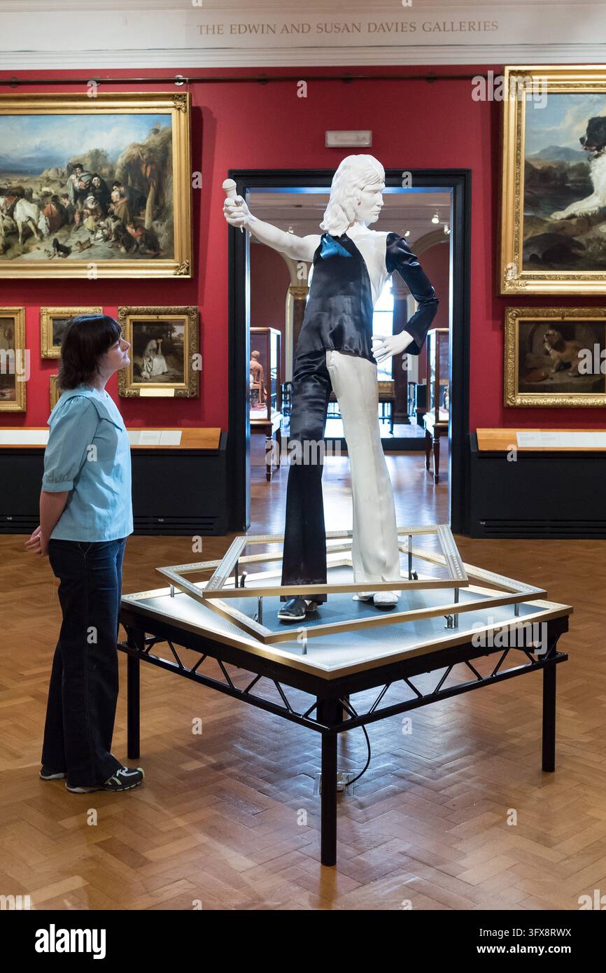 LONDRA, REGNO UNITO - 22 OTTOBRE 2026: Un membro dello staff osserva un ensemble monocromatico indossato da Freddie Mercury durante un precoce spettacolo dei Queen all'Imperial College (1973) durante un photocall per il Freddie Mercury Splendid Things Trail al V&A South Kensington a Londra, Regno Unito, il 22 ottobre 2026. Il trail, che aprirà il 24 ottobre e segna l'80º anniversario della nascita di Freddie, è stato sviluppato con Mary Austin, ex fidanzata, amica intima e confidente di Freddie per 20 anni, e celebra la carriera di Mercury attraverso costumi e accessori indossati in alcuni dei video musicali più memorabili Foto Stock