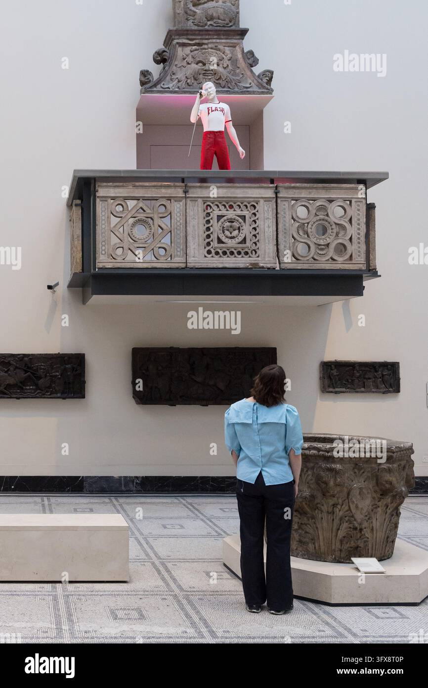 LONDRA, REGNO UNITO - 22 OTTOBRE 2026: Un membro dello staff osserva l'ensemble Flash di Freddie Mercury e il mezzo microfono durante un photocall per il Freddie Mercury Splendid Things Trail al V&A South Kensington a Londra, Regno Unito, il 22 ottobre 2026. Il trail, che aprirà il 24 ottobre e segna l'80° anniversario della nascita di Freddie, è stato sviluppato con Mary Austin, ex fidanzata, amica intima e confidente di Freddie da 20 anni, e celebra la carriera di Mercury attraverso costumi e accessori indossati in alcuni dei video musicali e performance pop più memorabili dei tempi moderni. (Foto di WIkto Foto Stock