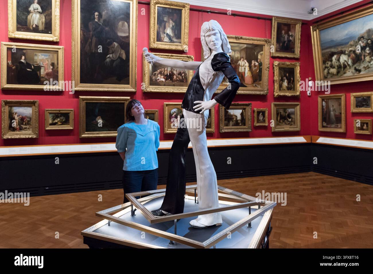 LONDRA, REGNO UNITO - 22 OTTOBRE 2026: Un membro dello staff osserva un ensemble monocromatico indossato da Freddie Mercury durante un precoce spettacolo dei Queen all'Imperial College (1973) durante un photocall per il Freddie Mercury Splendid Things Trail al V&A South Kensington a Londra, Regno Unito, il 22 ottobre 2026. Il trail, che aprirà il 24 ottobre e segna l'80º anniversario della nascita di Freddie, è stato sviluppato con Mary Austin, ex fidanzata, amica intima e confidente di Freddie per 20 anni, e celebra la carriera di Mercury attraverso costumi e accessori indossati in alcuni dei video musicali più memorabili Foto Stock