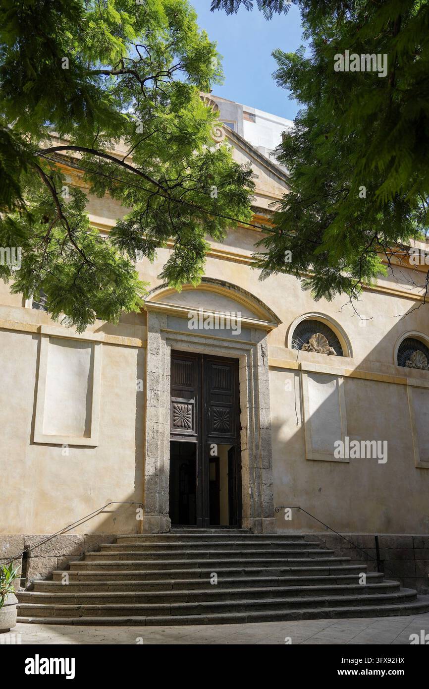Una facciata di chiesa ocra pallida con un semplice portale in pietra, un frontone triangolare, pannelli incassati e due finestre rotonde con decorazione a conchiglia si trova a Foto Stock