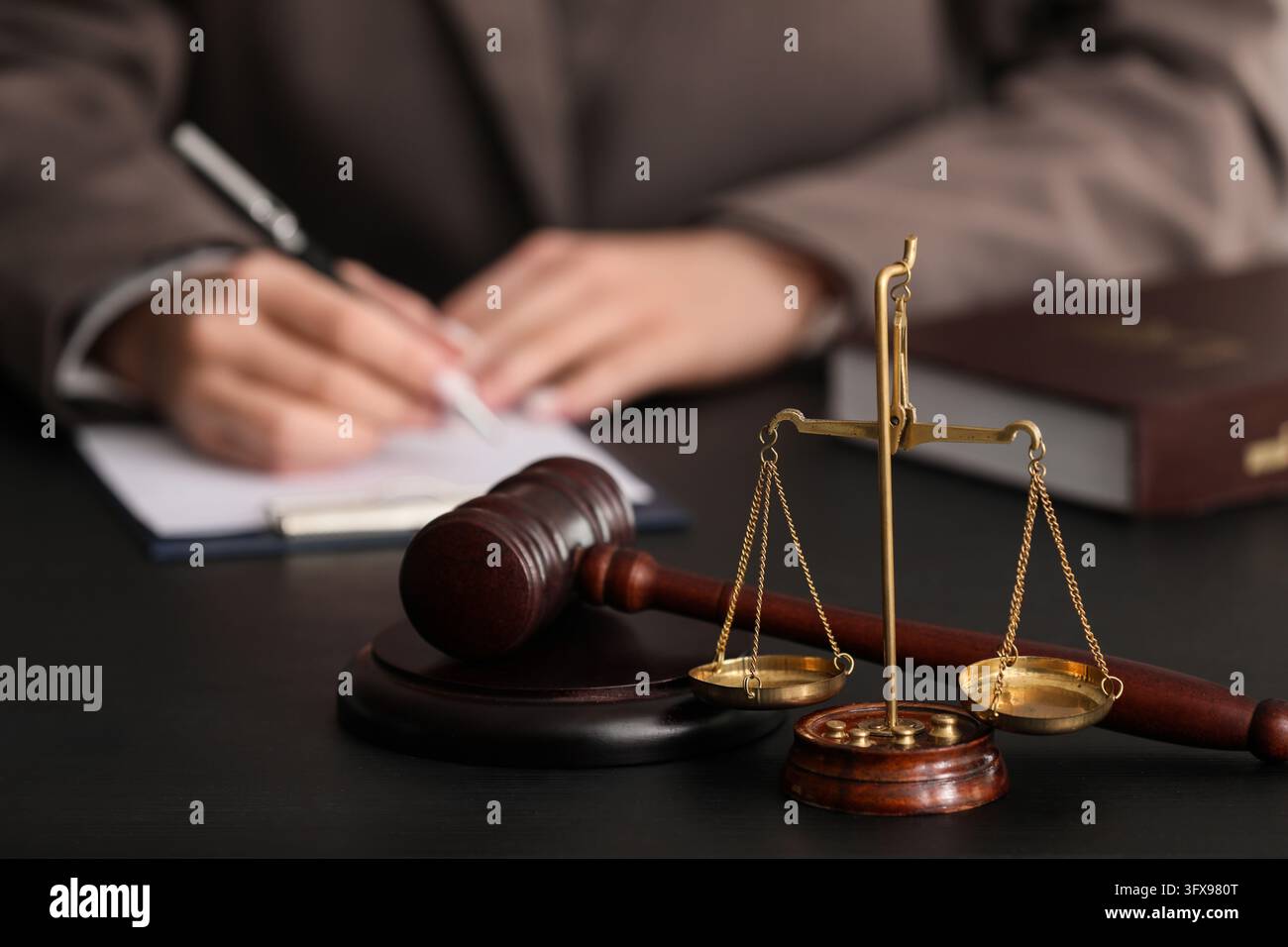 Giustizia legale e pratica legale, avvocato che firma documenti con martelletto di legno e bilancia di giustizia in ottone sulla scrivania in aula di tribunale o nello studio legale Foto Stock