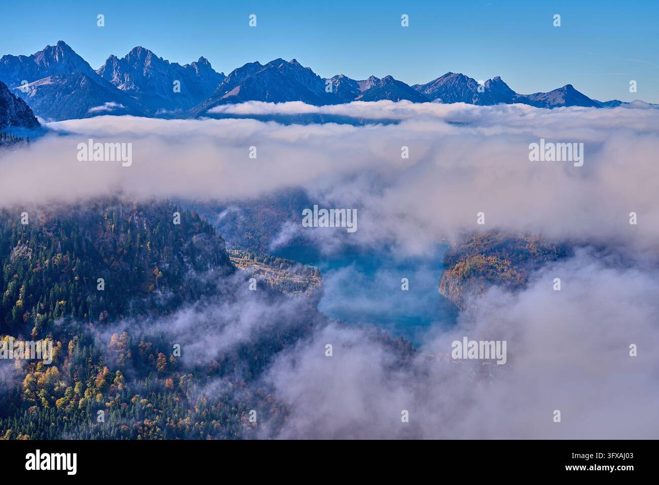 Copertura nuvolosa sull'Alpsee con panorama alpino. Una copertura nuvolosa si è posata sul Plansee, con il panorama alpino illuminato da una luce chiara dietro di essa. Foto Stock