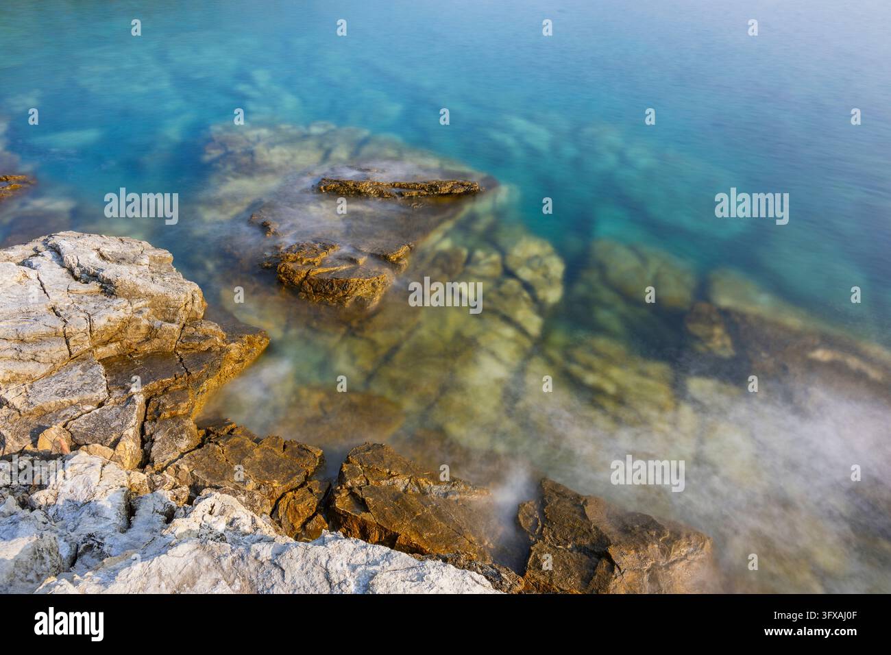Acque cristalline e turchesi sulla spiaggia di Ustrine Bay in una giornata di sole sull'isola di Cherso, lunga esposizione, Croazia Foto Stock