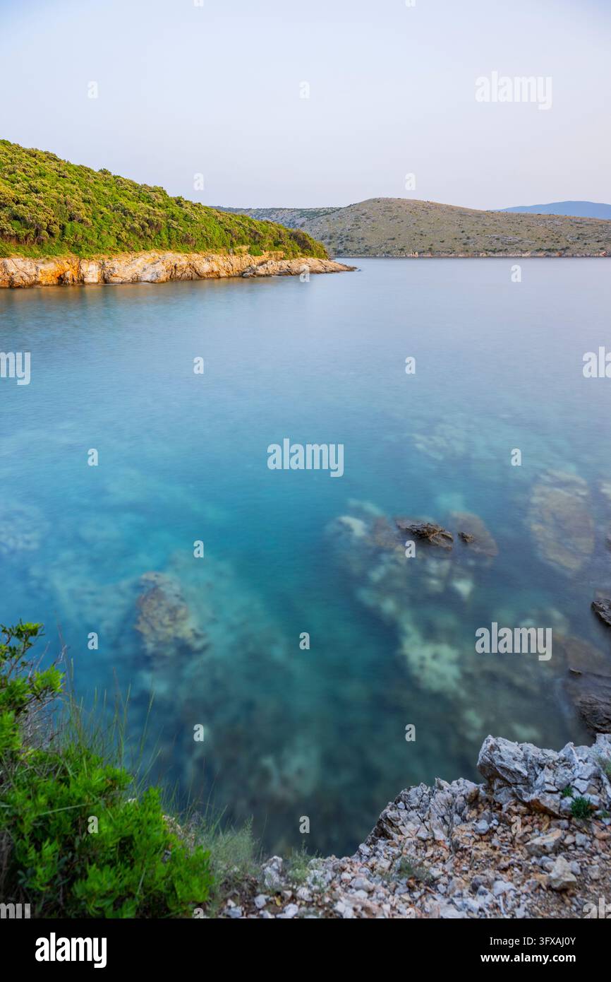 Acque cristalline e turchesi sulla spiaggia di Ustrine Bay in una giornata di sole al tramonto sull'isola di Cherso, lunga esposizione, Croazia Foto Stock